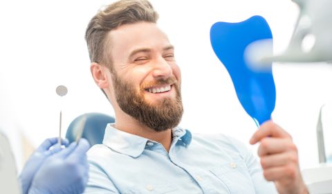 Handsome male patient looking at his beautiful smile sitting at the dental office